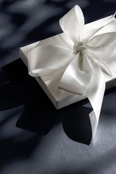 Anniversary celebration, shop sale promotion and luxe surprise concept - Luxury holiday white gift box with silk ribbon and bow on black background, luxe wedding or birthday present