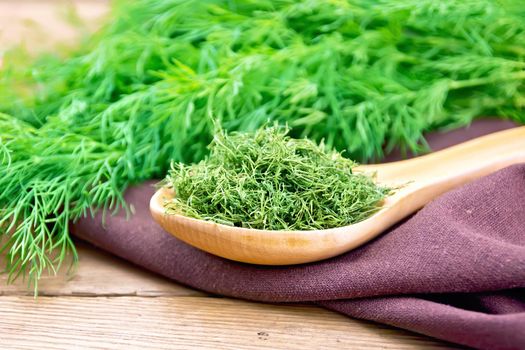 Dry dill in a spoon on a napkin, fresh herb on a wooden board background