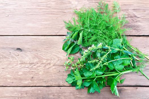 Sprigs of dill, savory, celery and mint on a wooden board background from above