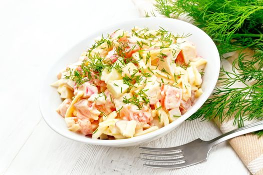 Salad of crab sticks, cheese, garlic, eggs and tomatoes, dressed with mayonnaise in a plate, napkin and parsley on the background of a light wooden board