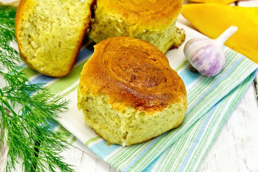 Pumpkin Scones with garlic and dill on a green napkin, yellow pumpkin slices on the background light wooden boards