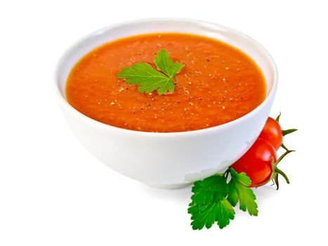 Tomato soup in a white bowl, parsley, tomatoes isolated on white background