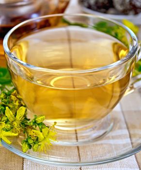 Tea in a glass cup and teapot, candy, fresh flowers tutsanon the linen tablecloth background