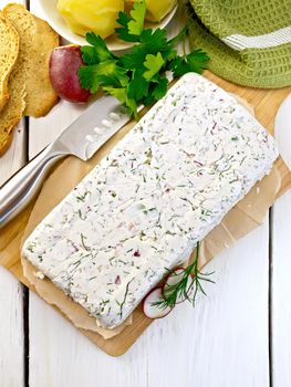 Terrine of curd and radish with dill, chives, knife on paper and board, bread, boiled potatoes, napkin, parsley on a light wooden planks
