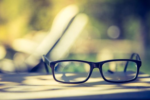 Black glasses and book outdoors in the park, summer time