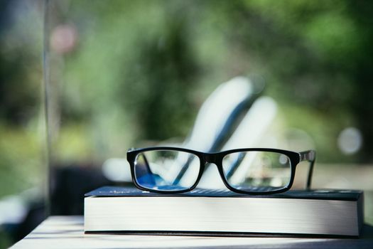 Black glasses and book outdoors in the park, summer time