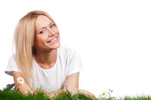 Beautiful young blonde woman lying on grass with chamomile flowers, isolated on white background