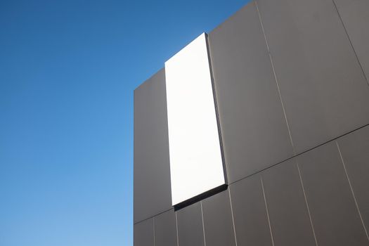 A Sign On The Side Of A Modern Commercial Retail Building, Blank For Your Text, With Blue Sky And Copy Space