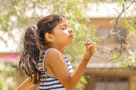 Little girl enjoying the smell of plants in nature