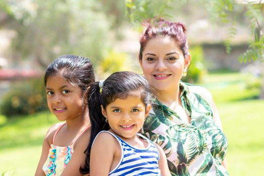 Love between a young mother and her two pretty daughters outdoors