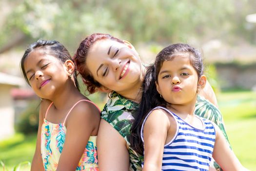 Love between a young mother and her two pretty daughters outdoors