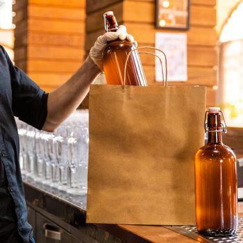 Restaurant worker putting beer bottle to shopping bag