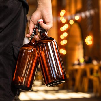 Man holding two beer glass in on hand, back view