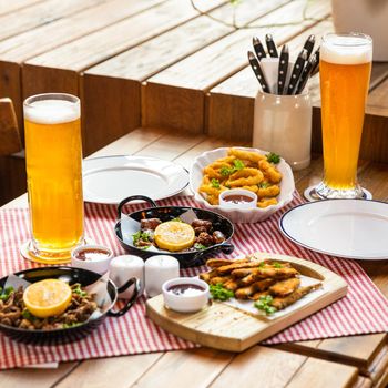 Tasty meat meal roulette with lemon, sprat and beer on the restaurant table