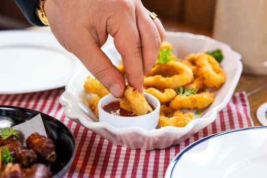 Man dipping calmar ring to the ketchup