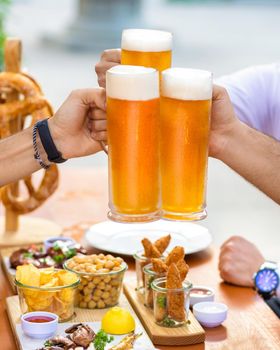 Clinking beer mugs outside, snacks on the table