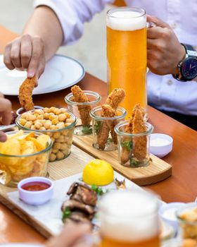 Man dipping fried chicken to the ketchup with beer