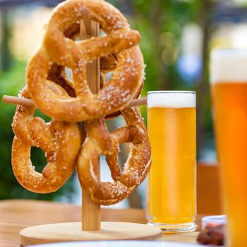 Beer mugs with pretzel on the table, green background