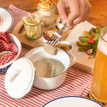 Man taking out hot German sausage with beer