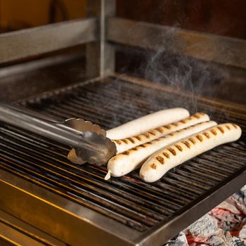 White German sausages cooking on charcoal