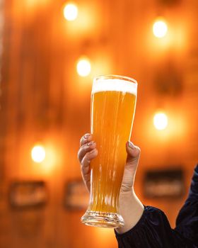 Woman holding beer mug, glass at the restaurant with bokeh background