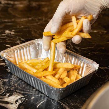 Chef putting french fries to the box