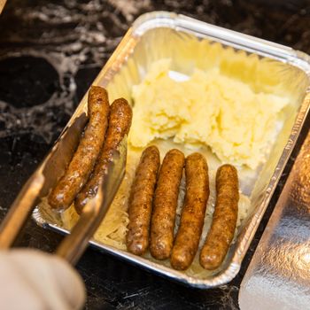 Chef putting white German sausages to the box