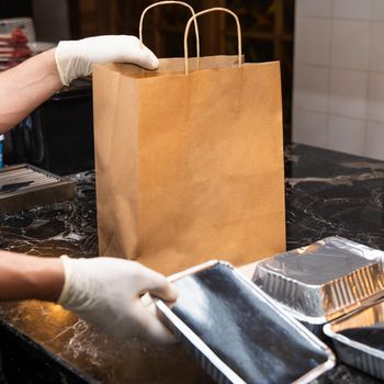Restaurant worker putting food boxes to the bag