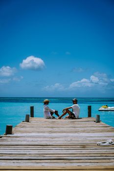 Palm Beach Aruba Caribbean, white long sandy beach with palm trees at Aruba Antilles, couple man and woman mid age on a white beach with palm trees