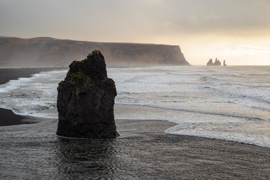 Rock formation on a black volcanic beach at Dyrholaey at sunset, Iceland