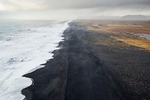 View of the black sand beach from Dyrholaey promontory on Atlantic South Coast in a cloudy day, Iceland