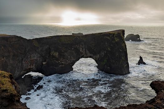 Natural arch of Dyrholaey Peninsula in South Iceland in a cloudy day