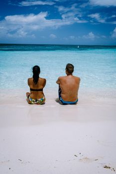 Palm Beach Aruba Caribbean, white long sandy beach with palm trees at Aruba Antilles, couple man and woman mid age on a white beach with palm trees