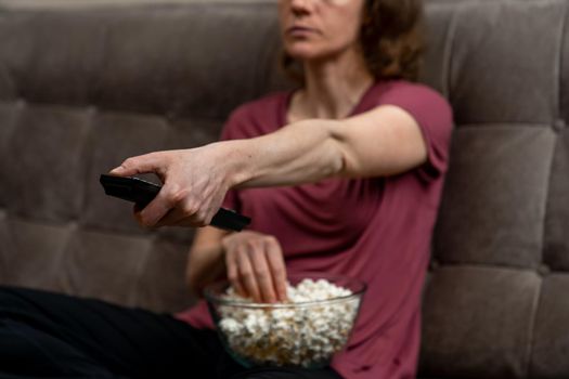 switch channel to tv using driver. woman with a bowl of popcorn.