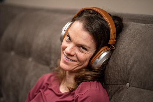 young woman with wireless headphones on her head on the couch.