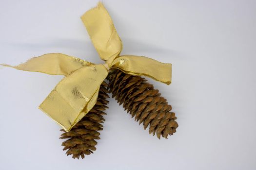 A gold bow and two brown fir cones on a white background.The concept of the New Year.Place for the text.