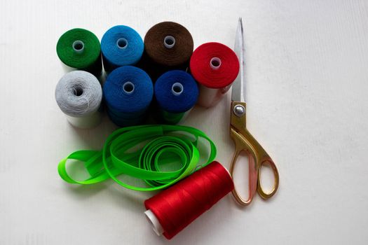 Colorful threads and scissors on a white background.