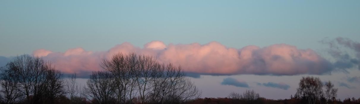 Beautiful panorama of orange and yellow clouds at sunrise and sunset in a blue sky