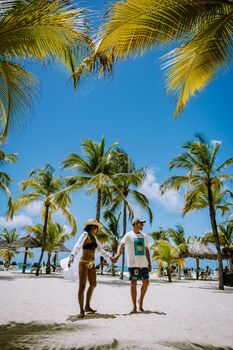 Palm Beach Aruba Caribbean, white long sandy beach with palm trees at Aruba Antilles, couple man and woman mid age on a white beach with palm trees