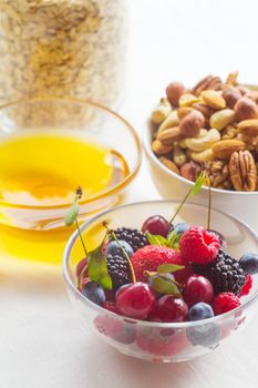 Honey oatmeal, nut and flax seeds granola in a bowl with and fresh berries on white background cereal healthy breakfast concept