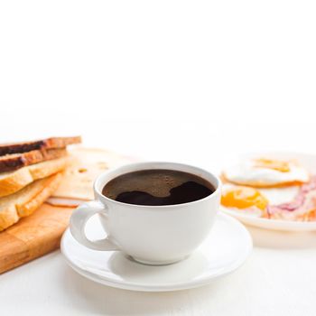 Breakfast with coffee, toasted bread, eggs, bacon, cold cuts and cheese on table