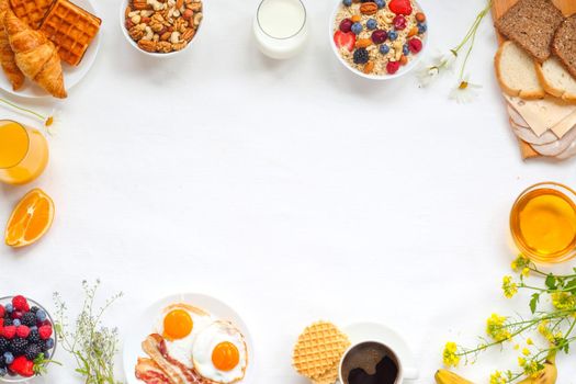 Healthy breakfast with muesli, fruits, berries, nuts, coffee, eggs, honey, oat grains and other on white background. Flat lay, top view, copy space for text, frame