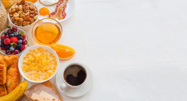 Healthy breakfast with muesli, fruits, berries, nuts, coffee, eggs, honey, oat grains and other on white background. Flat lay, top view, copy space for text, frame