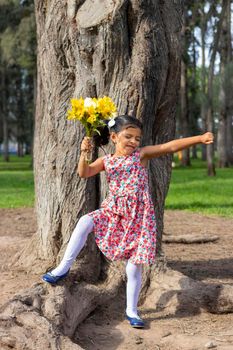 Little girl in dress celebrating in the park with a bouquet of flowers in her hand