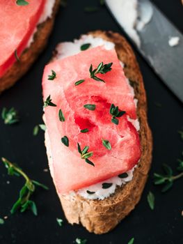 Toasts with soft cheese, watermelon and fresh thyme.Salty cheese,sweet watermelon and spicy thyme on crispy grilled bread slices. Idea and recipe for unusual healthy breakfast, summer snack or lunch