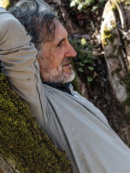 senior man resting on a tree in the woods