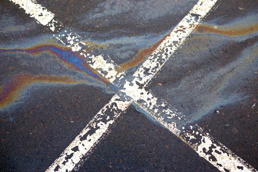 Gas stain on wet asphalt in the car park caused by a leak under a car or truck, abstract background