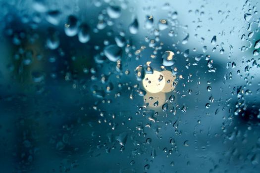 Water drops on the side window of the car. View from the inside of the car during the rain on the evening city street. Soft selective focus