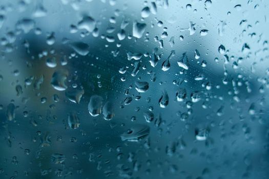 Water drops on the side window of the car. View from the inside of the car during the rain on the evening city street. Soft selective focus