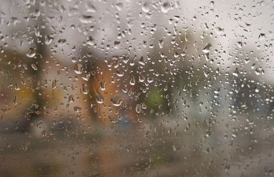 Water drops on the side window of the car from inside the car during rain on a city street.Soft selective focus